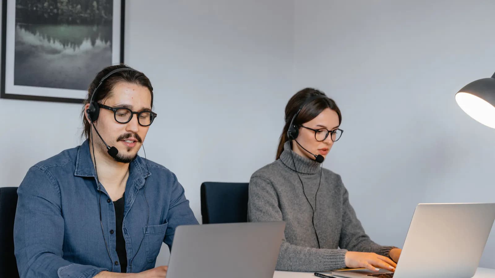 A support agent wearing a headset sits at a desk, looking at the screen while replying to a customer message.