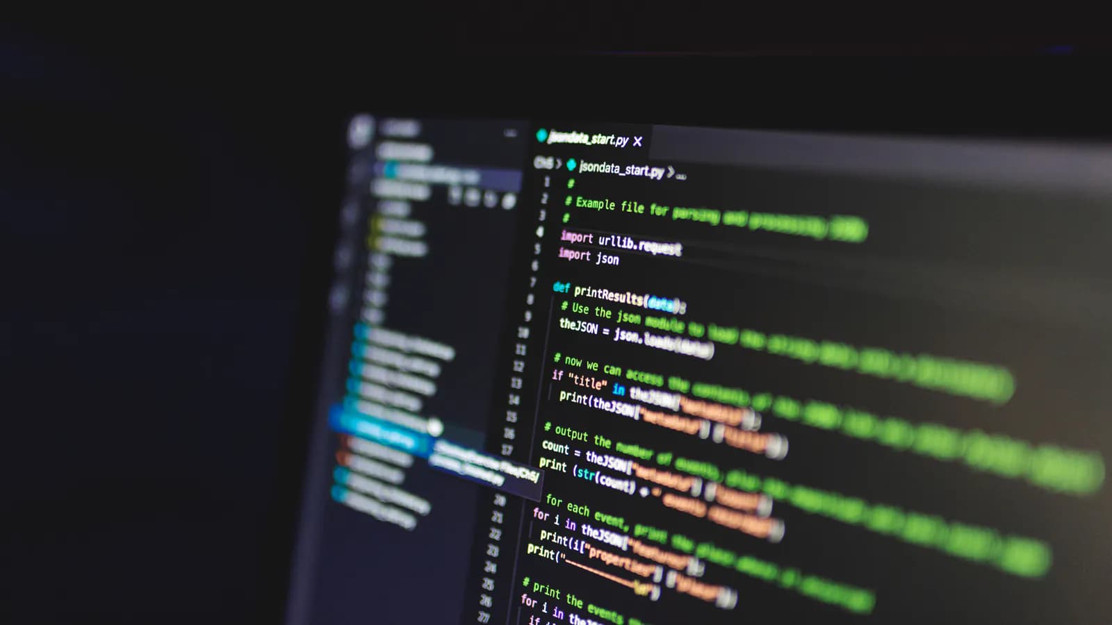 A code editor open on a screen in a dark room, with line numbers down the left, syntax-highlighted code in the middle and a file list in the sidebar.