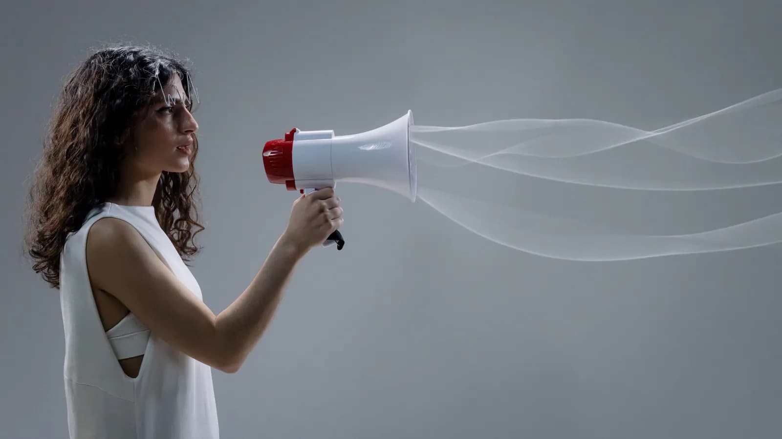 A side-on portrait of a woman in white holding a red-and-white megaphone, with stylised sound waves flowing out of its horn.