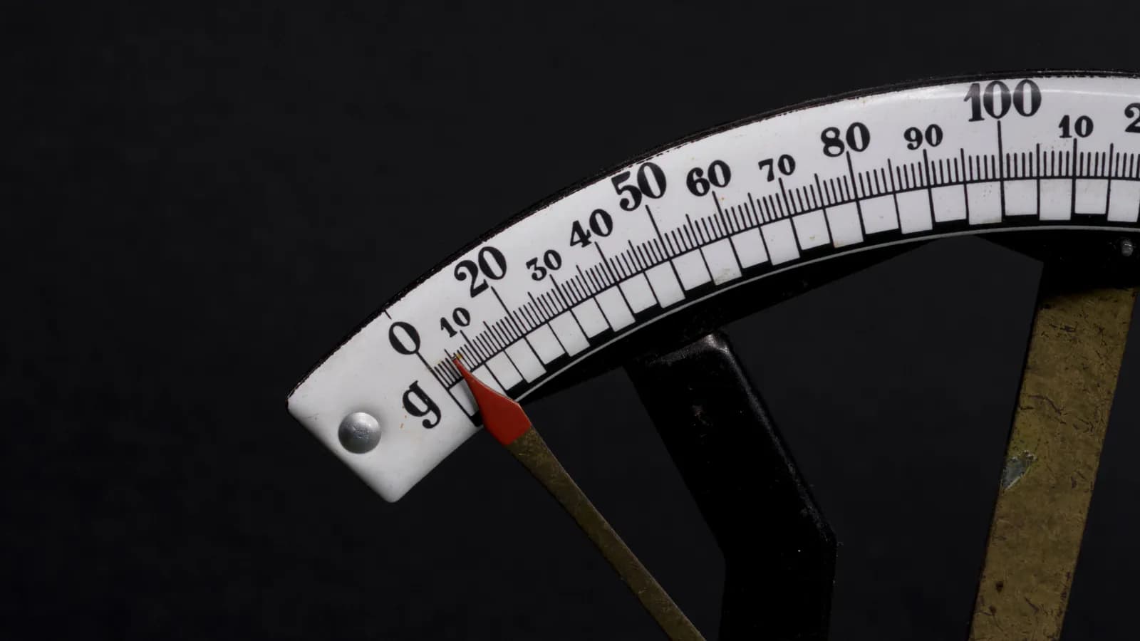 The dial of an analogue scale against black: the red needle still resting on zero, graduations running from 0 to 100 — before you measure there is no number.