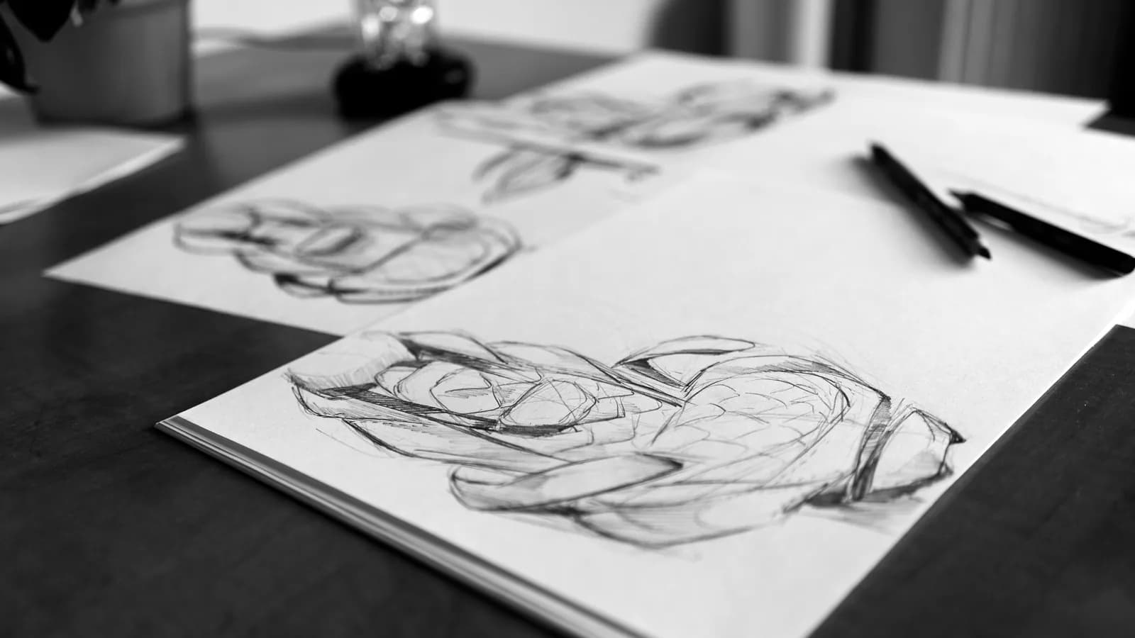 A hand-drawn website layout sketch on paper at a designer's desk, with a pencil and colored notes marking the sections.