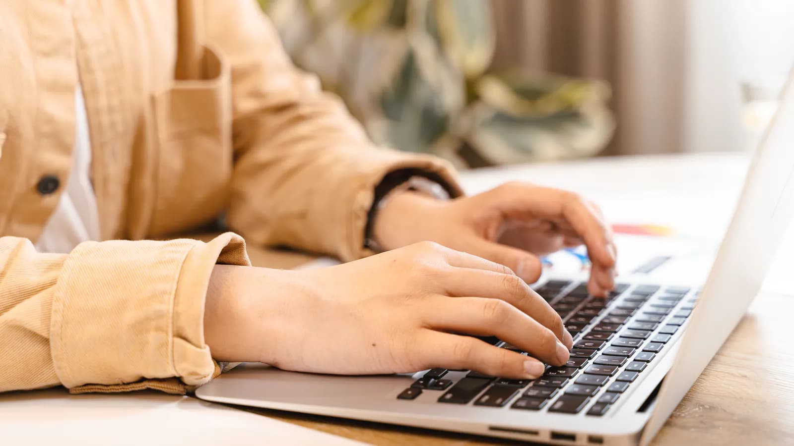 A person sits in front of a laptop with a thoughtful expression, a cup of coffee nearby, a desk in the background — the moment of thinking before writing a reply.