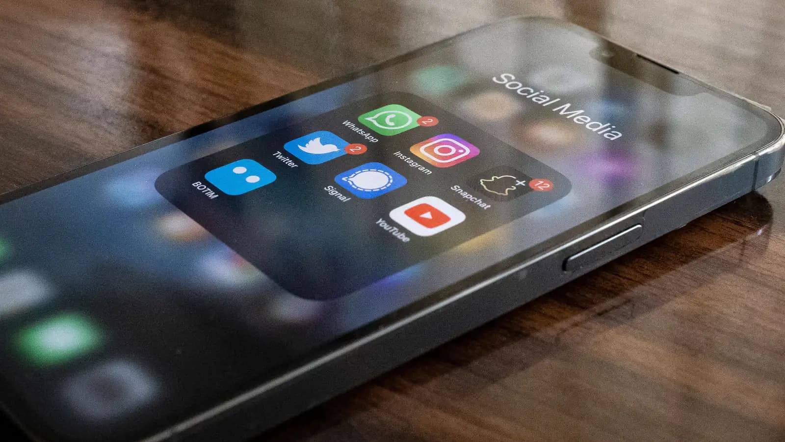 Close-up of a smartphone screen showing several social media app icons, a finger reaching toward the display.