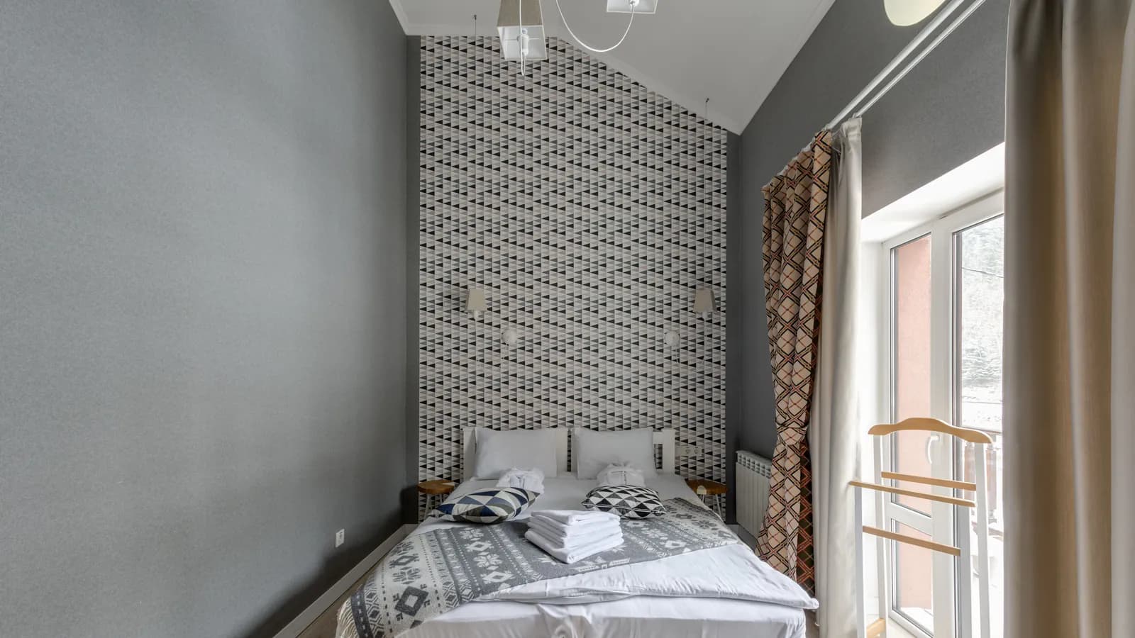 A hotel room with a neatly made white bed, sunlight streaming in through the window.