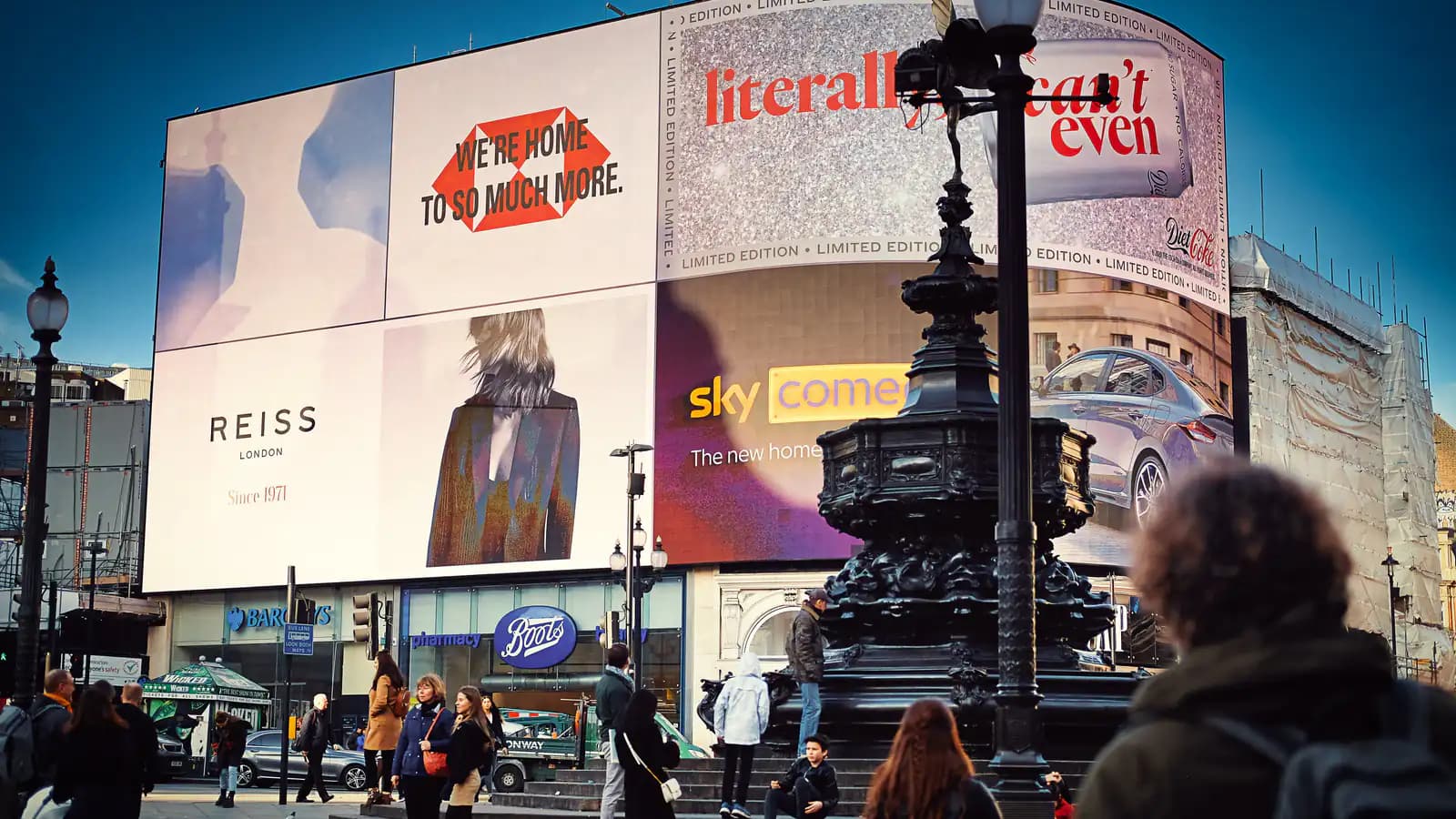 A large billboard mounted on a city street wall, with pedestrians walking past it without a glance.