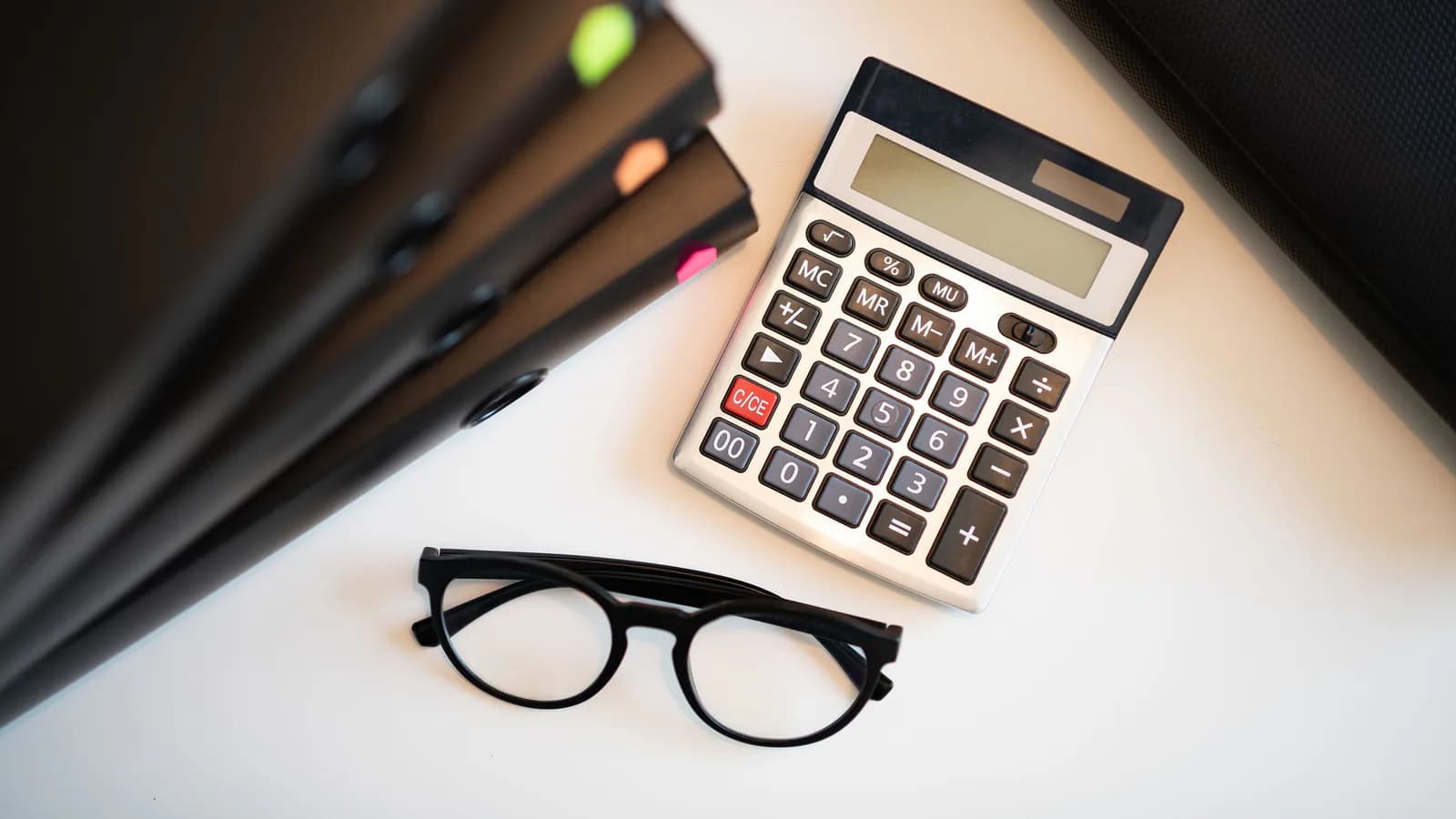 An invoice, a calculator and a pen laid out on a desk — the working scene of pricing out a project.