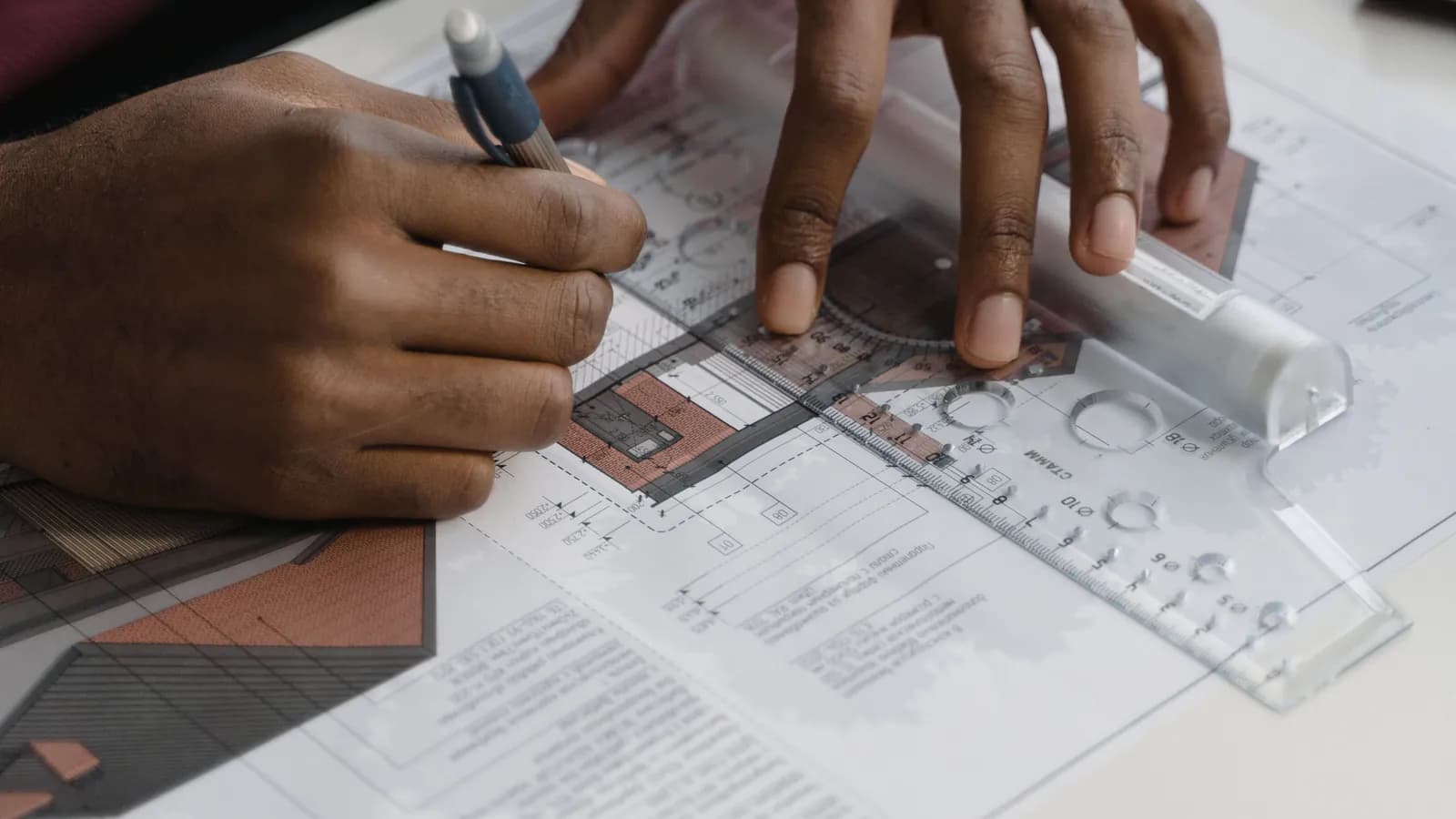 An open technical specification document lies on a desk next to an architectural sketch — a project being planned on paper.