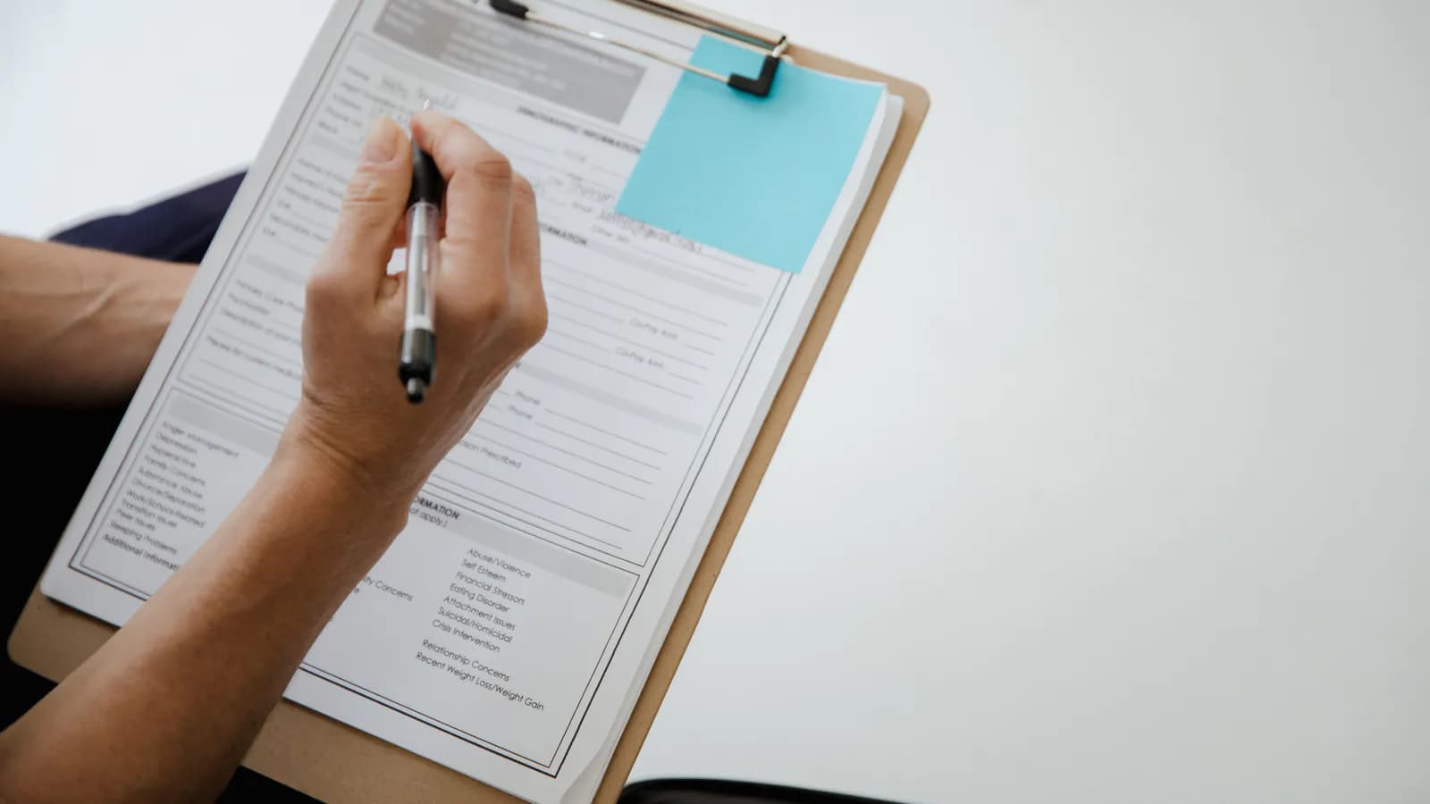 A closed notebook with a pen clipped on top, resting beside a checklist with several items already ticked off — the visual of a technical review in progress.